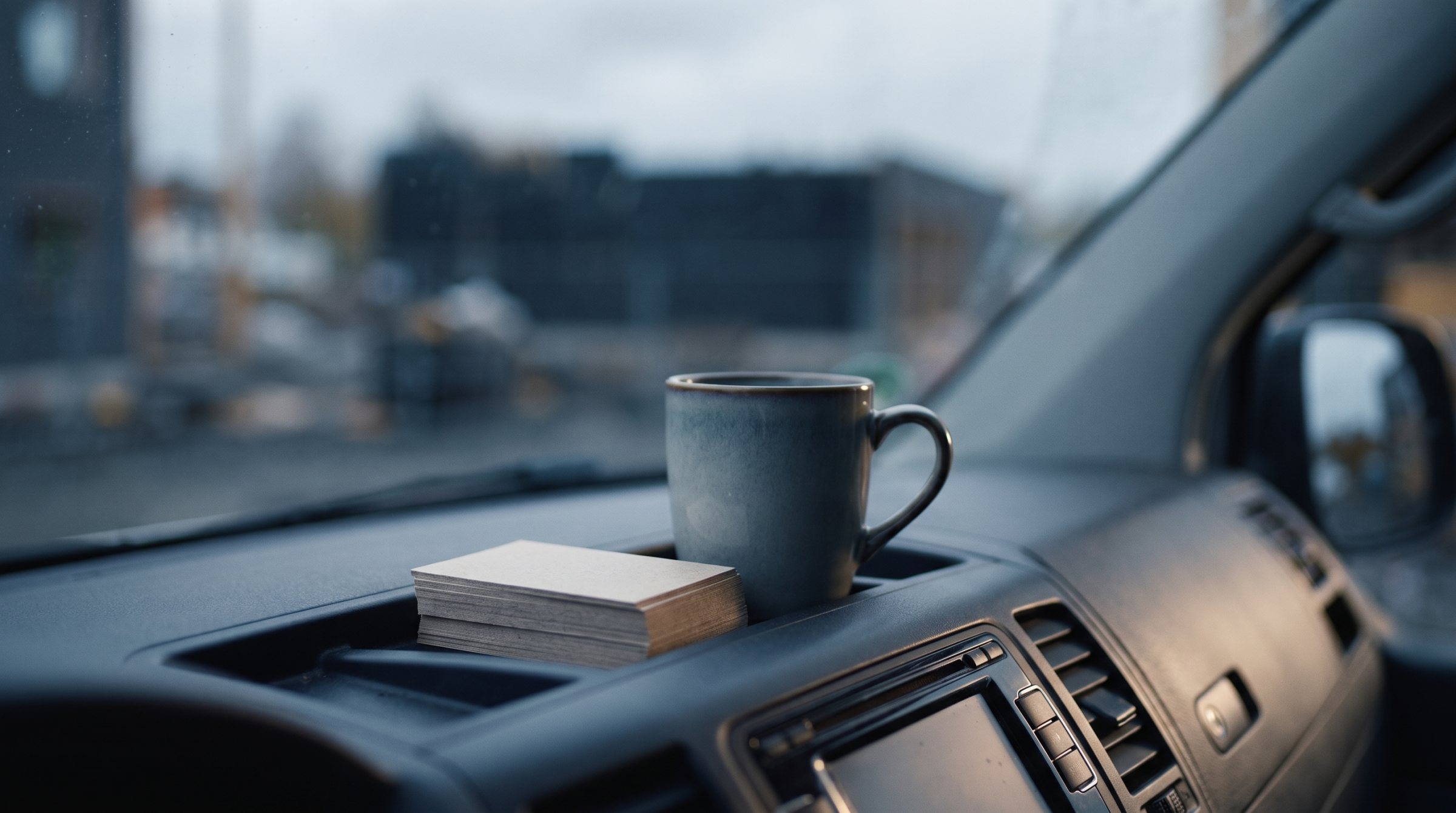Visittkort og kaffekopp på dashbordet i en varebil